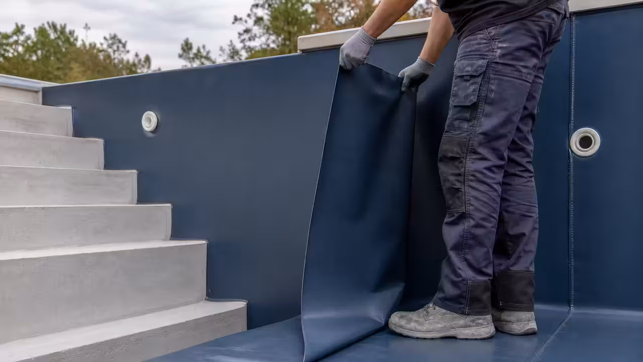 Pose d’une membrane armée bleue dans un bassin de piscine en béton aux parois préparées