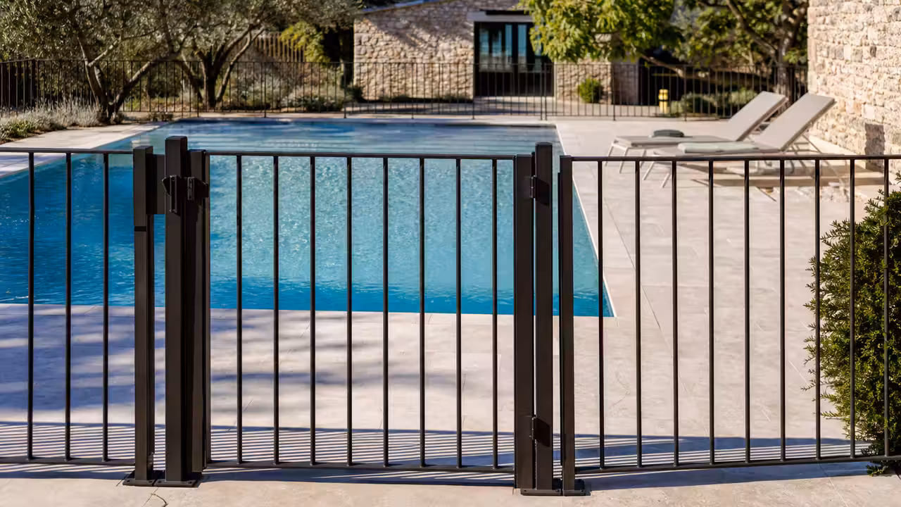 Barrière en aluminium avec portillon sécurisé installée autour d’une piscine familiale sur terrasse minérale