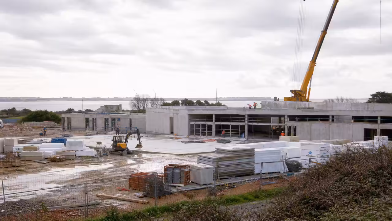 Chantier d’un futur centre aquatique municipal sur un site côtier breton, avec engins et structures en construction
