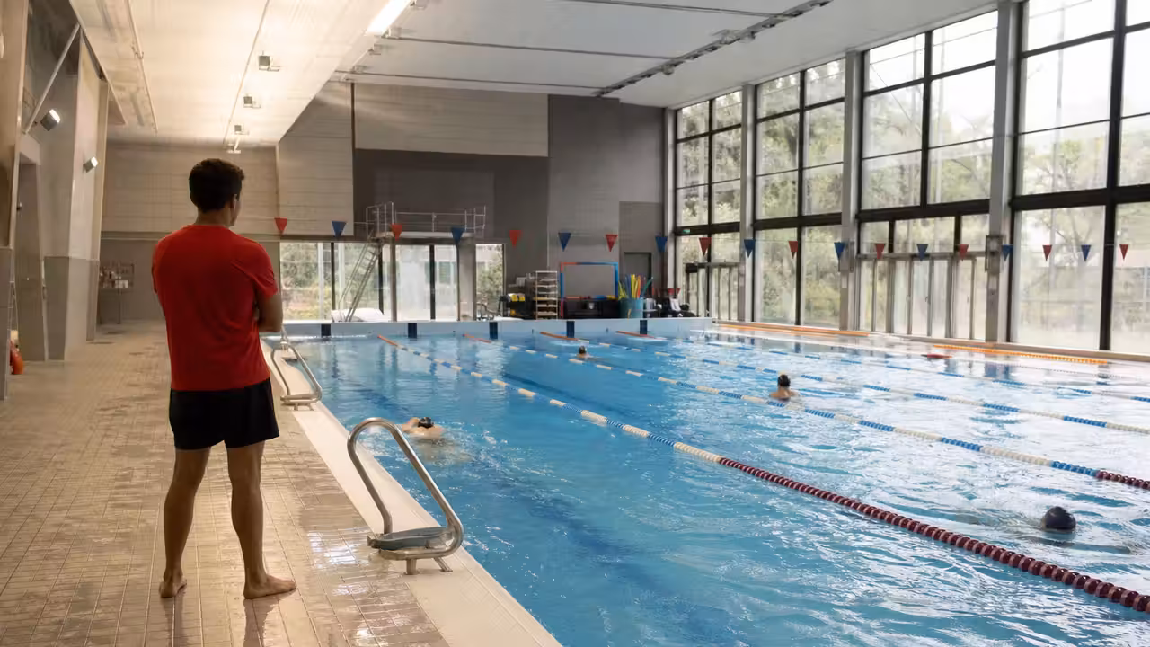 Nageurs de différents âges dans les lignes d’eau d’une piscine municipale lumineuse et surveillée