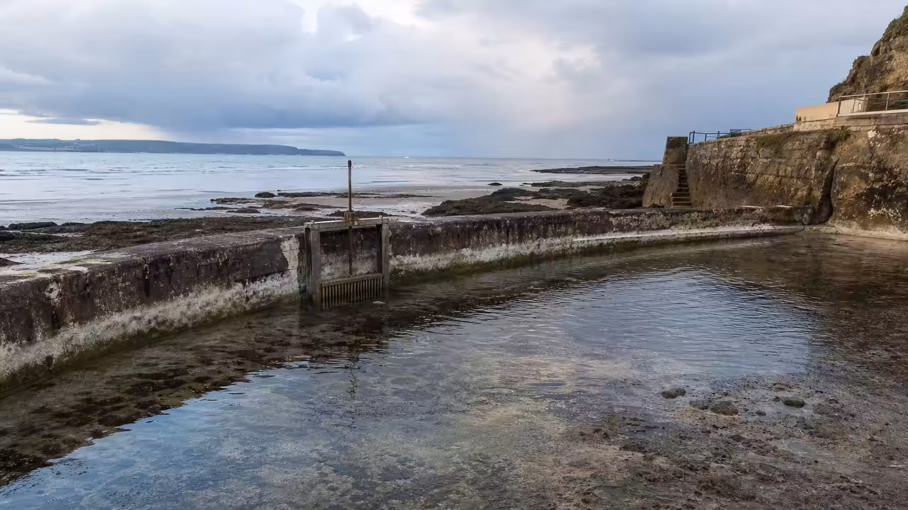 Bassin de mer du Plat Gousset à Granville à marée basse, avec murets et eau de la Manche