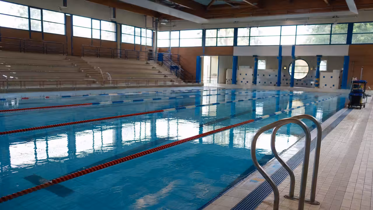 Bassin couvert vide pendant une intervention technique, avec lignes d’eau et matériel de maintenance