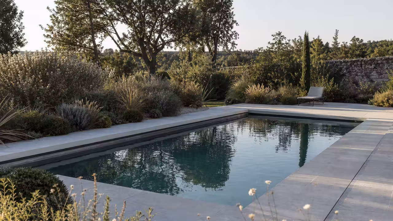Bassin rectangulaire compact bordé de pierre claire et de végétaux dans un jardin contemporain français