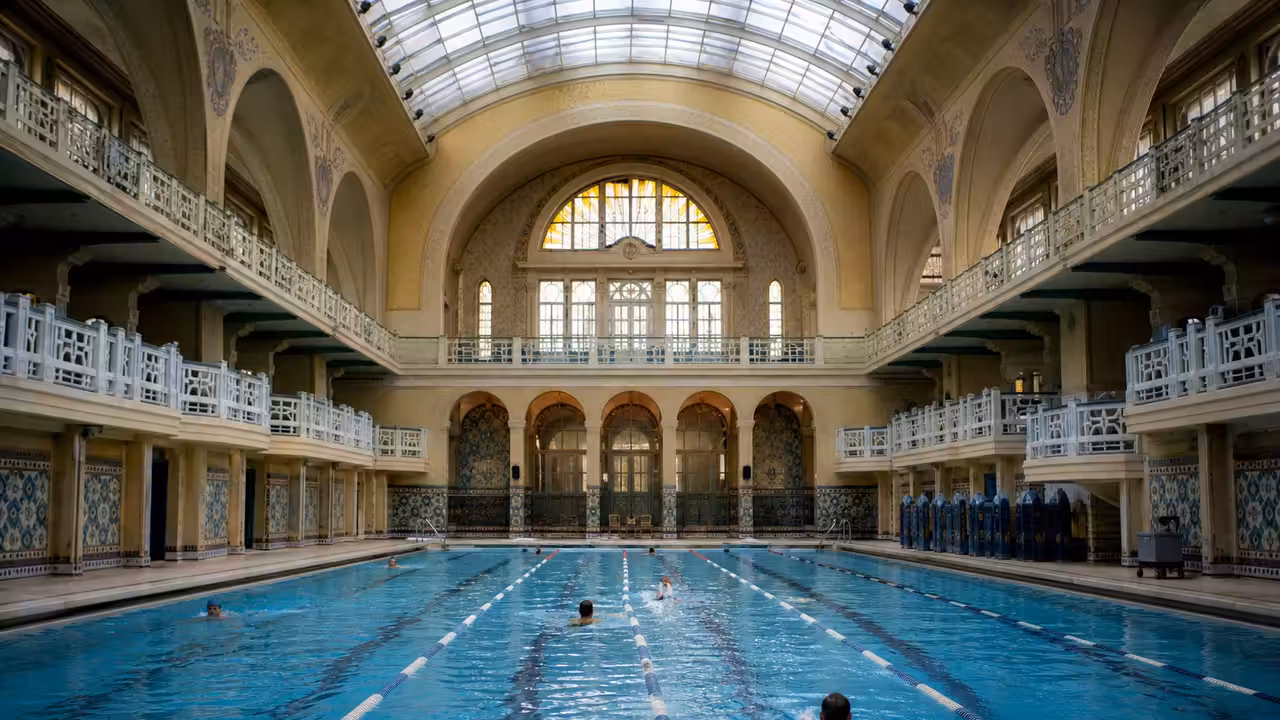 Bassin couvert parisien historique avec verrière, carrelages anciens et lignes d’eau calmes