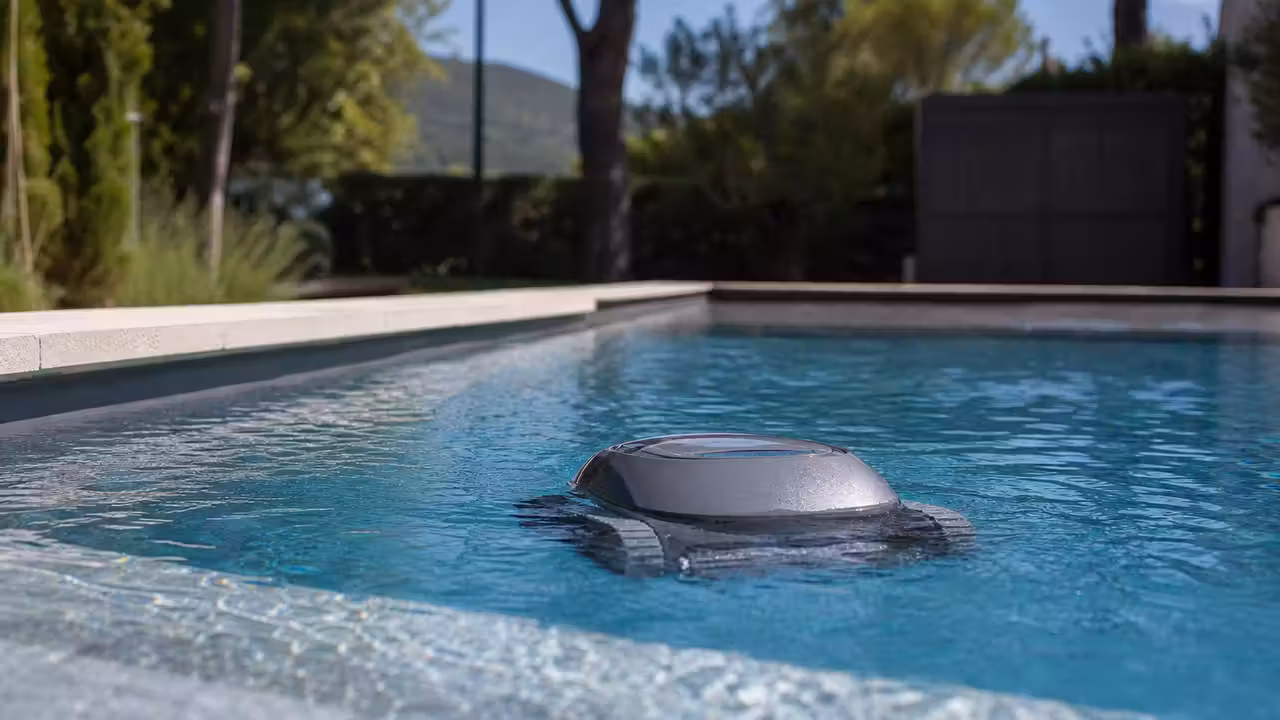 Robot de nettoyage autonome circulant dans une piscine moderne près d’un local technique bien entretenu
