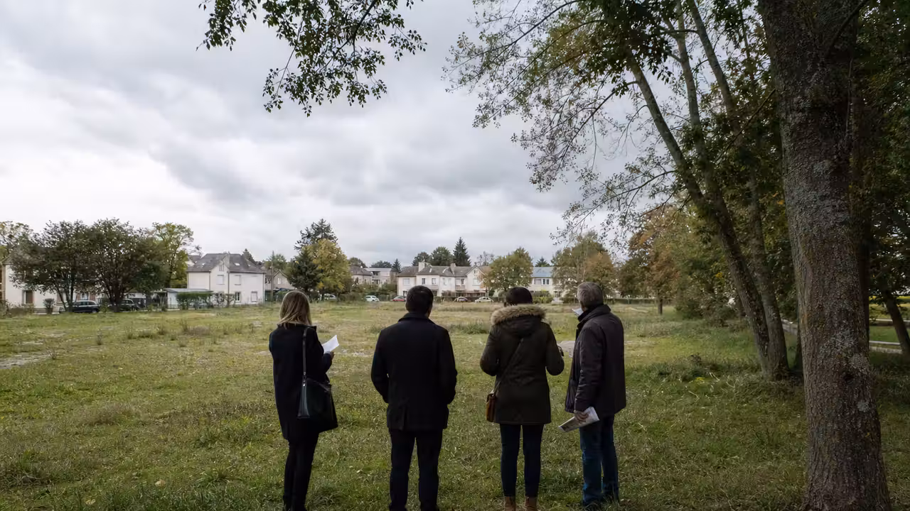 Terrain réservé à un équipement public, bordé d’arbres et de logements, illustrant les enjeux d’implantation d’une piscine.