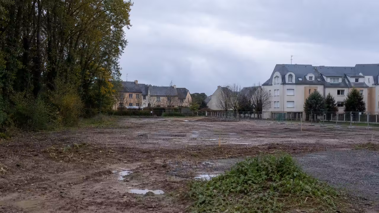 Ancienne friche urbaine arborée en bord de ville, envisagée pour accueillir un centre aquatique public
