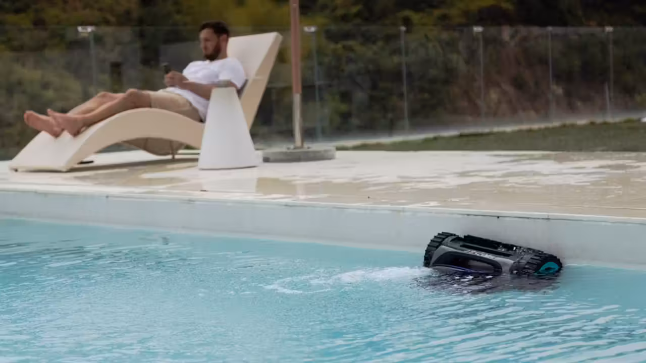 Robot électrique nettoyant le fond d’une petite piscine avec plage immergée et escalier large