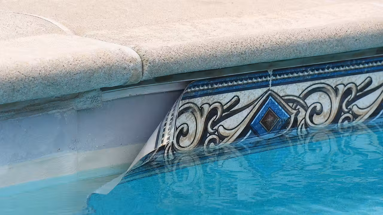 Frise de ligne d'eau de piscine décollée par plaques dans un angle du bassin près de la margelle