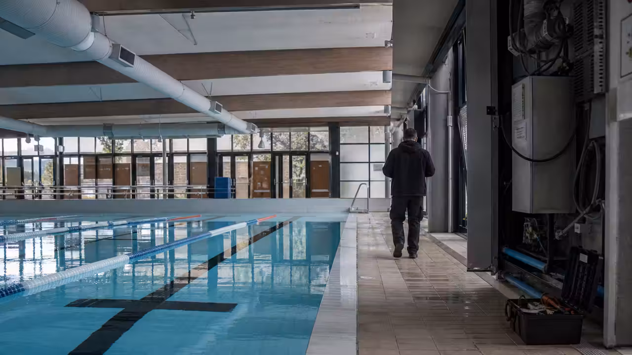 Bassin couvert municipal vide, couloirs de nage et système de ventilation visibles au plafond