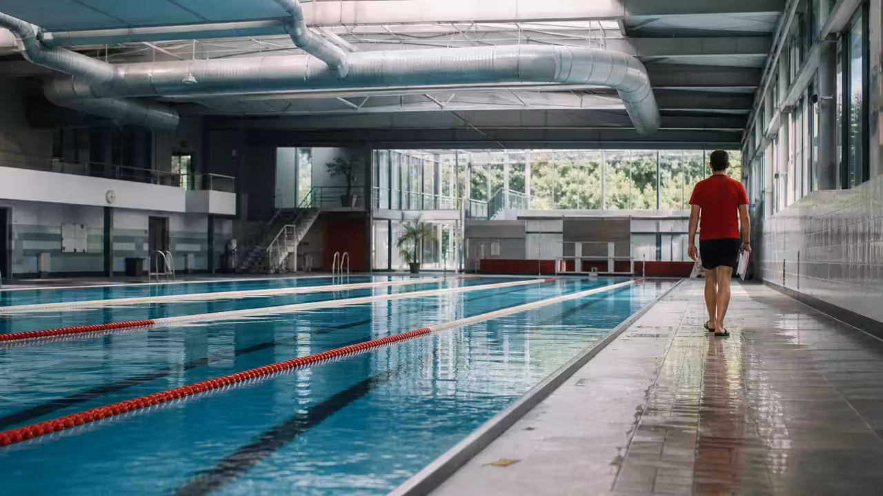 Intérieur d’une piscine municipale couverte avec lignes d’eau, baies vitrées et système de ventilation au plafond
