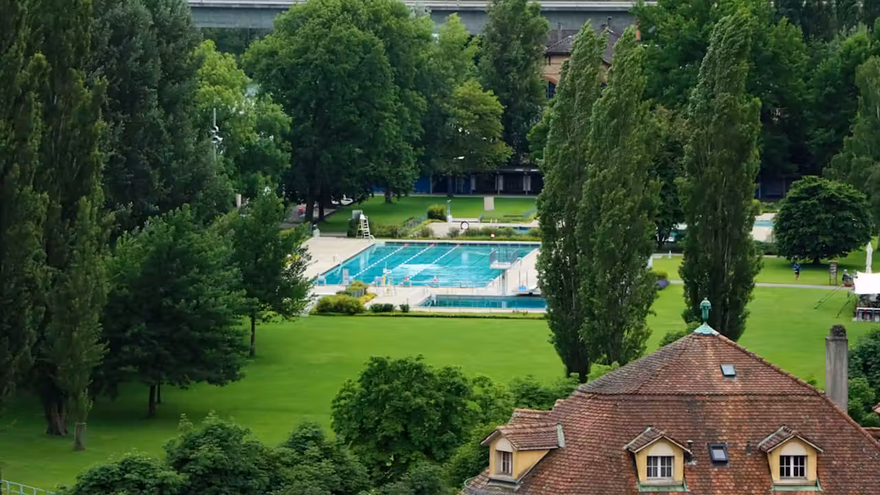 Bassin extérieur vide de la piscine du Rhône à Lyon, avec plages minérales et installations techniques en arrière-plan