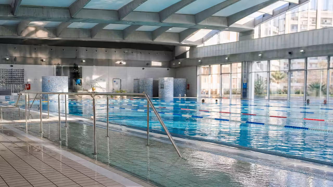 Intérieur lumineux d’une piscine municipale rénovée avec bassin, lignes d’eau et accès de plain-pied