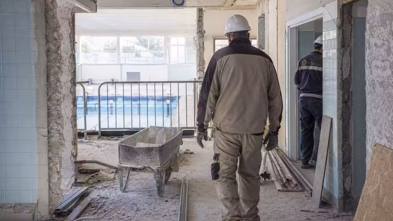 Chantier de rénovation d’une piscine publique avec zone d’accueil et vestiaires en cours de démolition