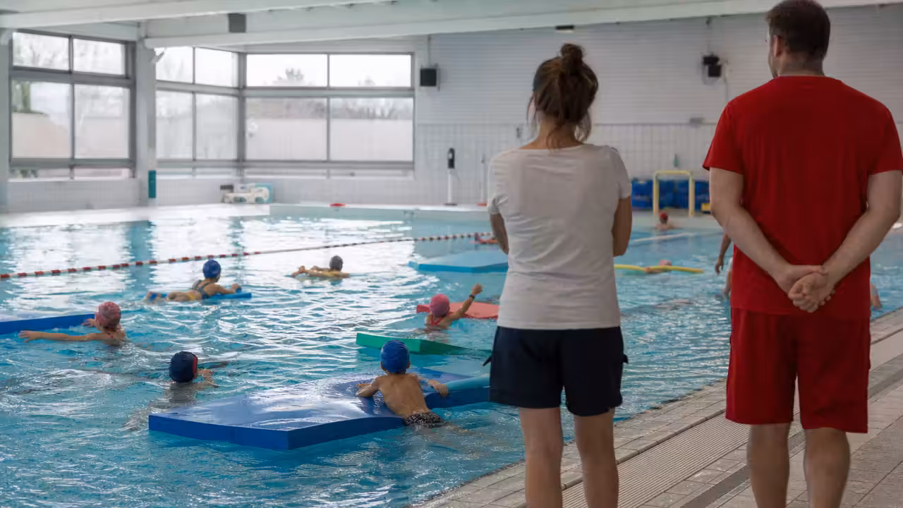 Bassin municipal aménagé pour une séance scolaire avec tapis flottants et repères colorés sécurisés