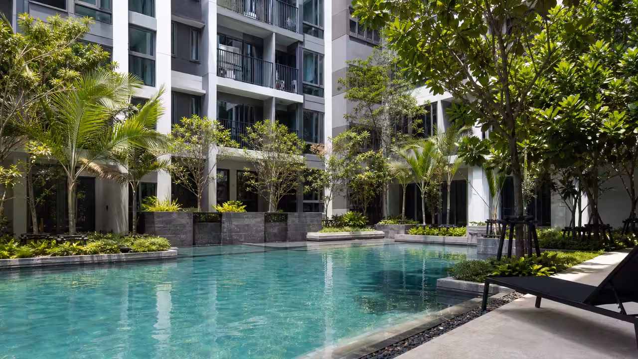Piscine extérieure d’une résidence moderne entourée de végétation tropicale et de logements à Hua Hin