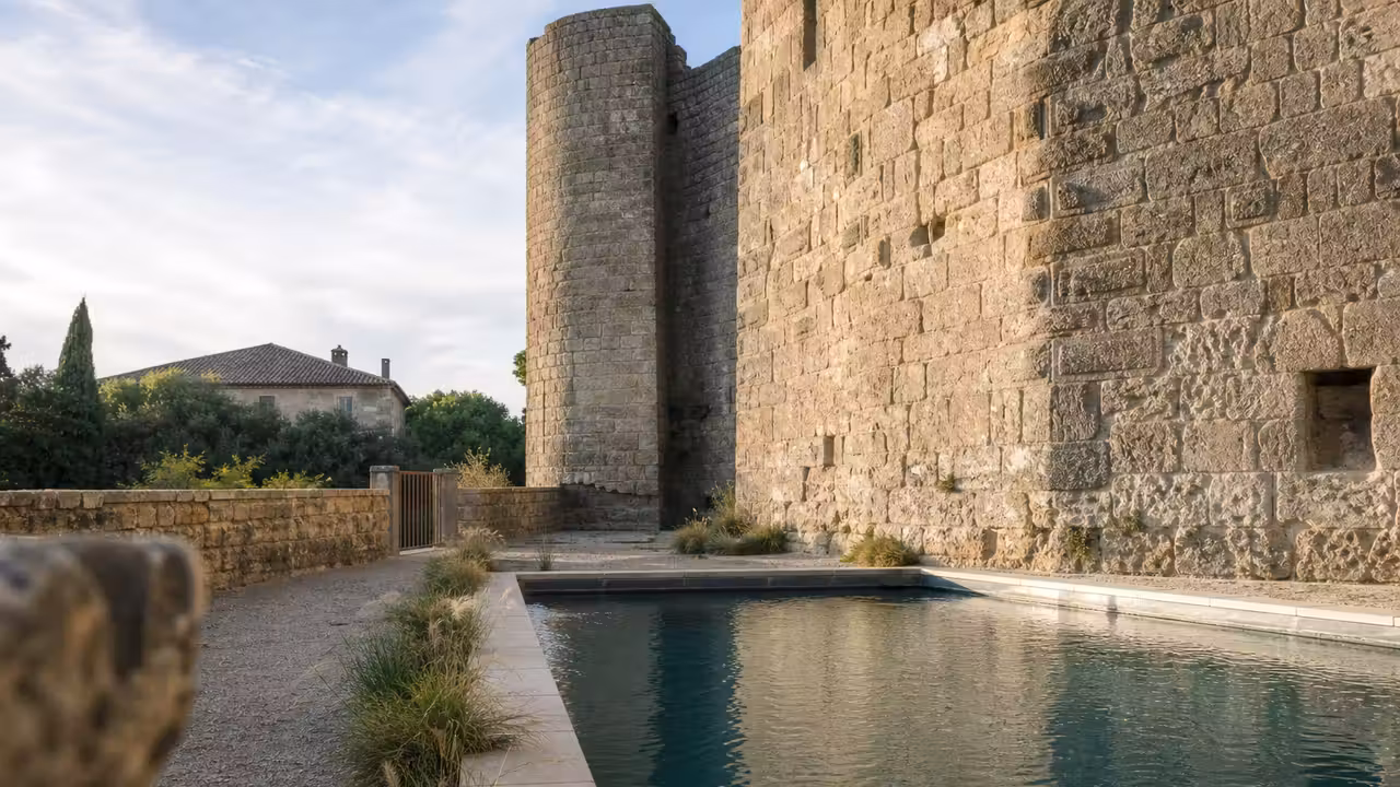Piscine rectangulaire discrètement aménagée au pied des murs en pierre d’un château ancien