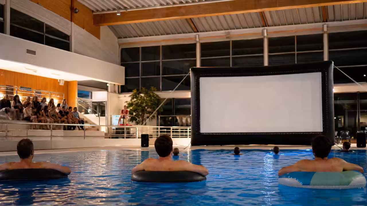 Écran de cinéma gonflable face à un bassin intérieur lors d’une animation aqua-ciné familiale