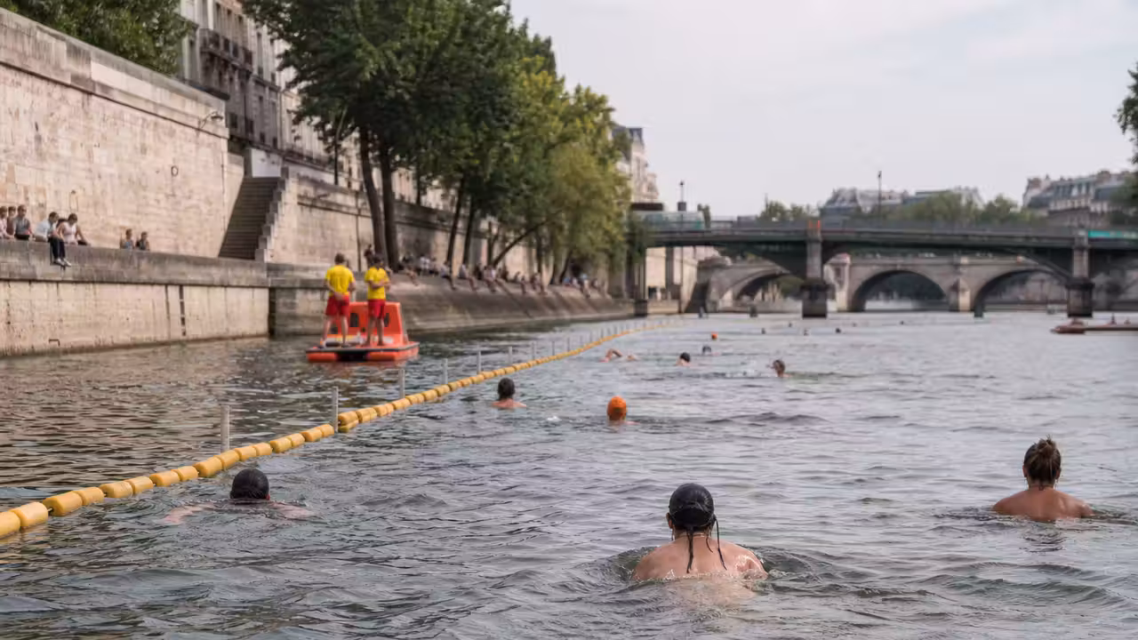 Baigneurs encadrés par des surveillants dans une zone délimitée de la Seine, avec les quais parisiens en arrière-plan