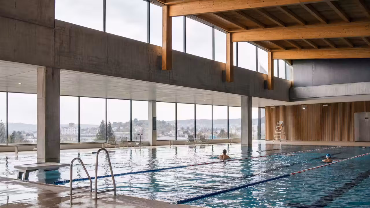 Bassin intérieur lumineux d’une piscine publique moderne avec lignes de nage et grande baie vitrée