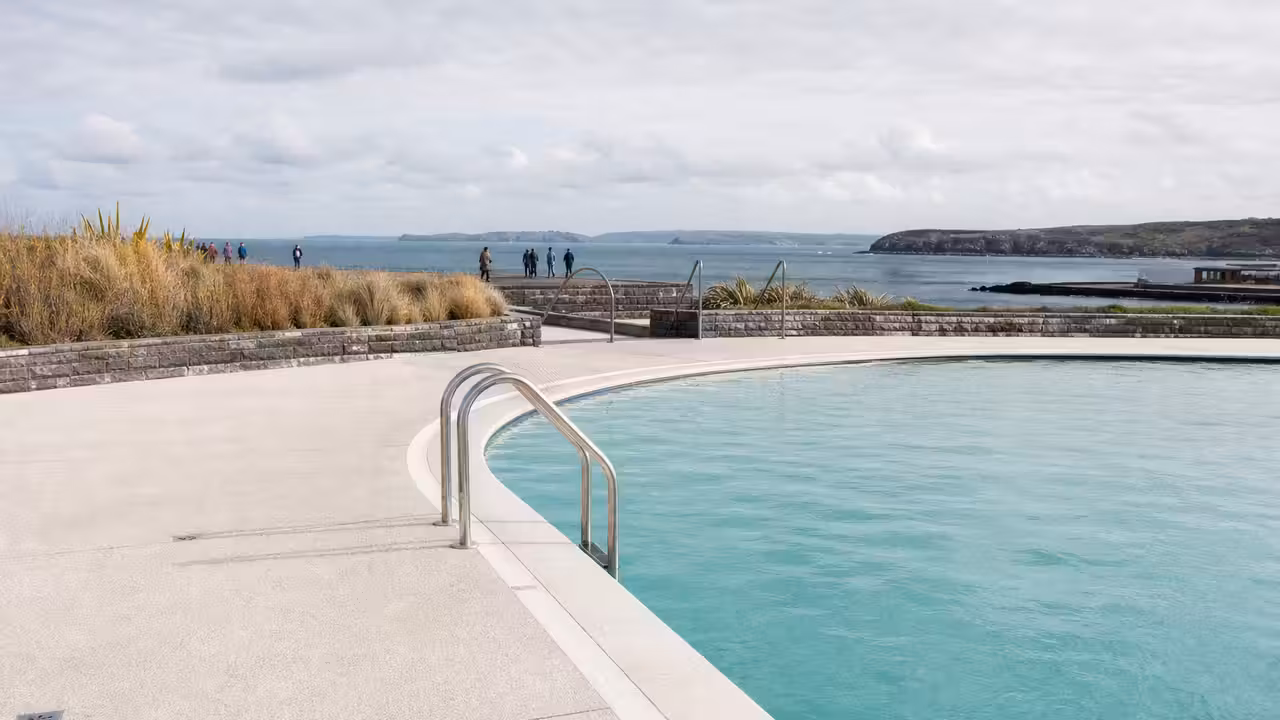 Bassin extérieur de type Lido face au littoral, avec promenade minérale et végétation résistante au vent