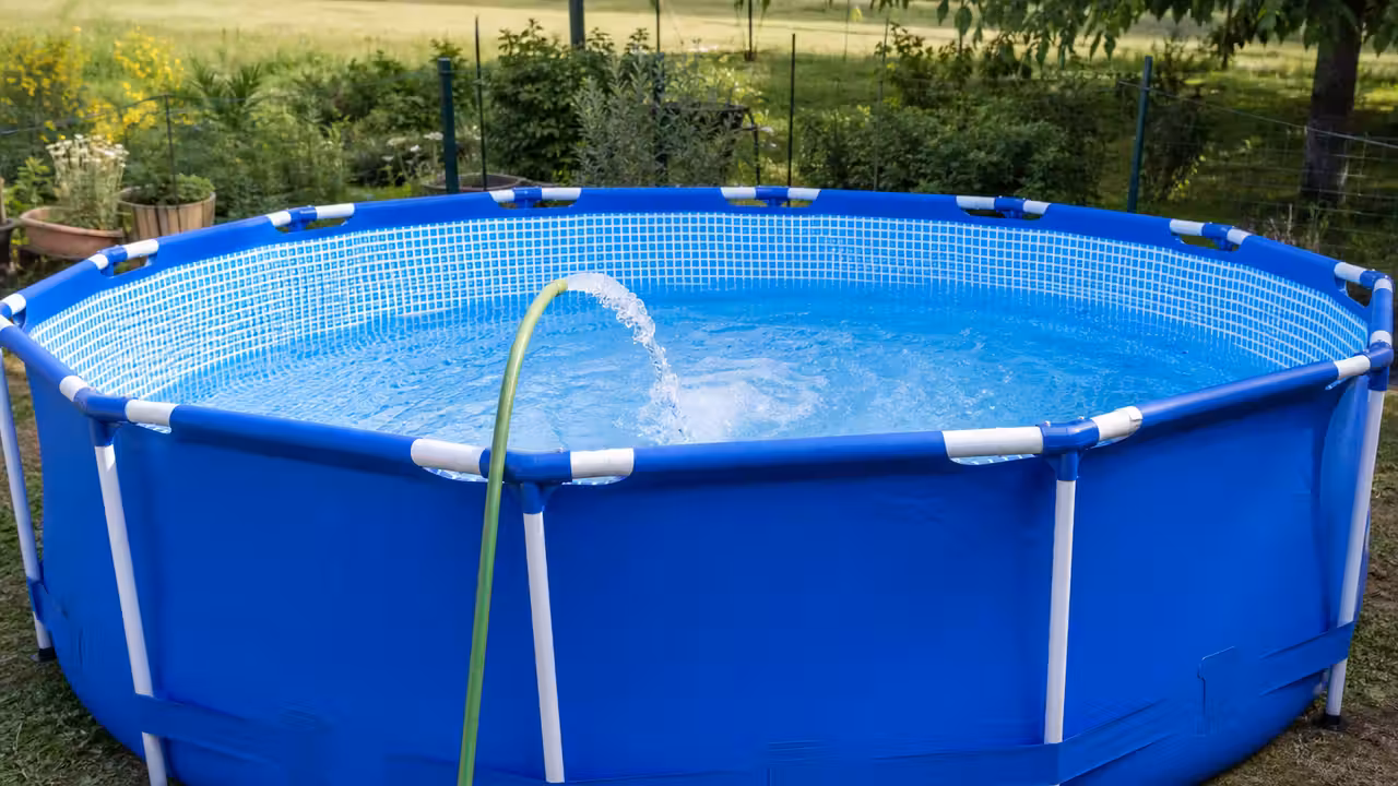 Piscine hors-sol neuve en cours de remplissage avec sa structure en PVC bleu encore brillante