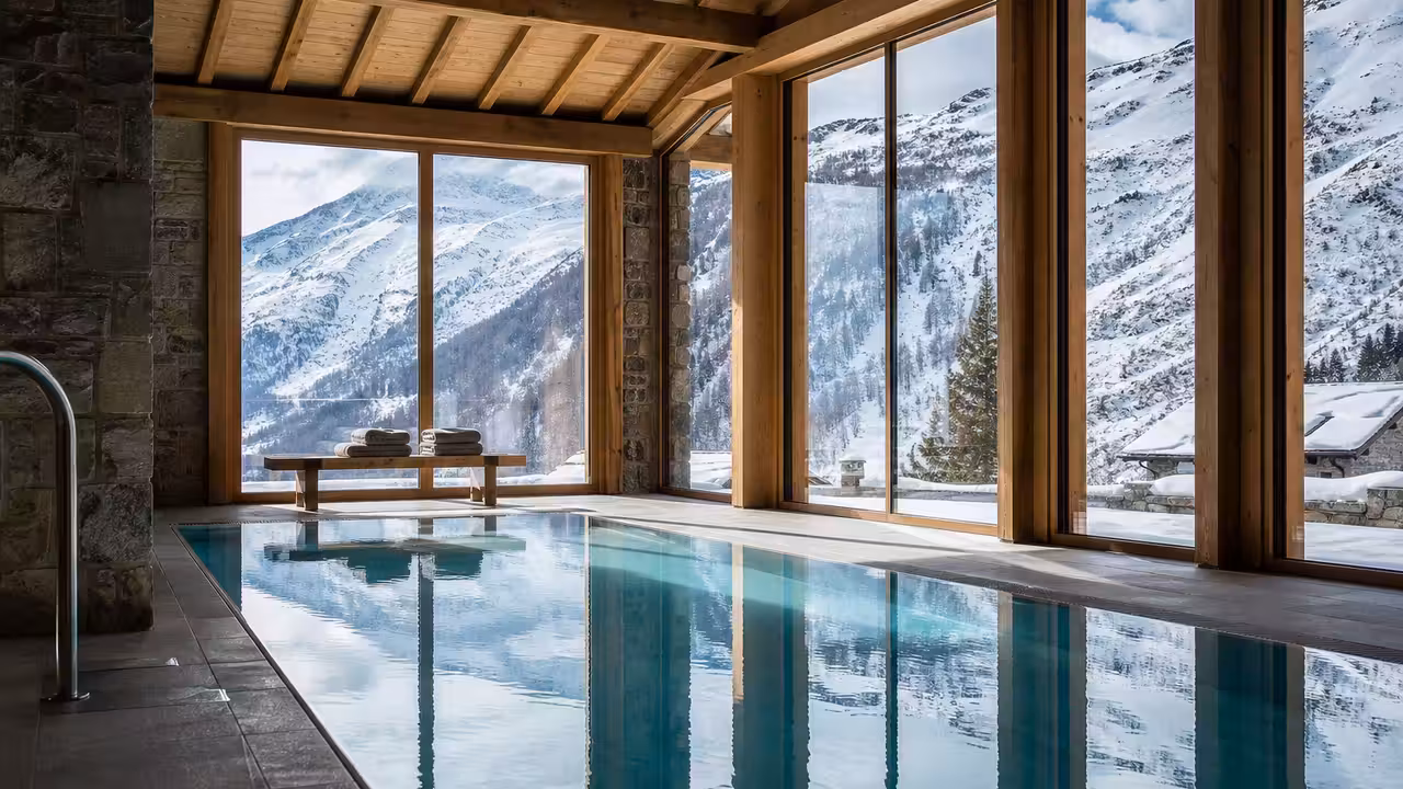 Piscine intérieure chauffée dans une résidence de montagne, avec baies vitrées ouvrant sur les sommets enneigés