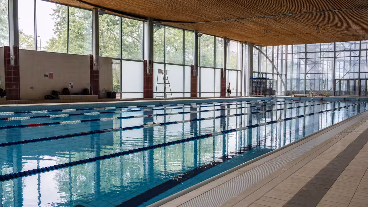 Bassin sportif couvert d’une piscine municipale avec lignes d’eau calmes avant l’arrivée des nageurs