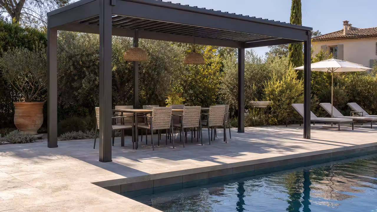 Pergola en aluminium à lames orientables installée sur une terrasse en pierre au bord d’une piscine