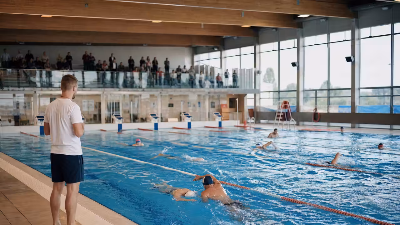 Participants de tous âges lors d'un relais ludique encadré dans un bassin de piscine publique