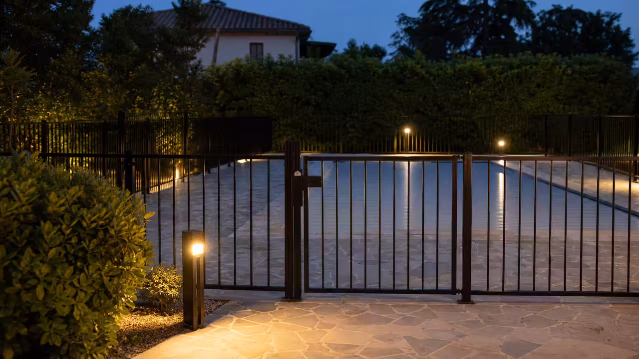 Portillon verrouillé d’une barrière de sécurité entourant une piscine privée couverte dans un jardin