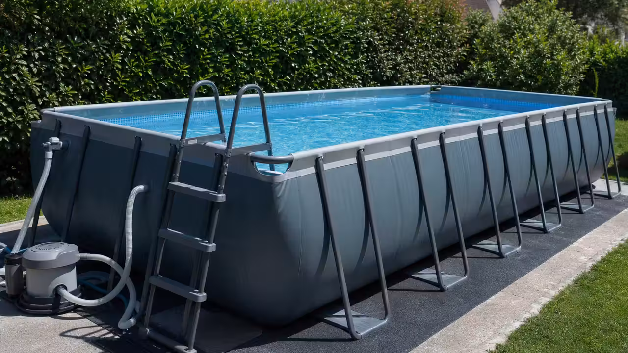 Grande piscine tubulaire rectangulaire installée sur un jardin nivelé, avec filtration et bâche à proximité
