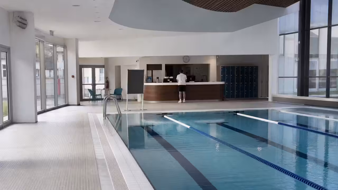 Couloirs de nage vides dans une piscine publique, avec affichage d’information à l’entrée des vestiaires
