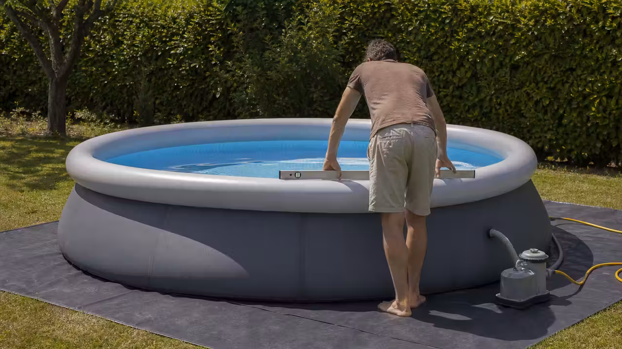 Piscine gonflable familiale autoportante installée sur un tapis de sol dans un jardin plat et dégagé