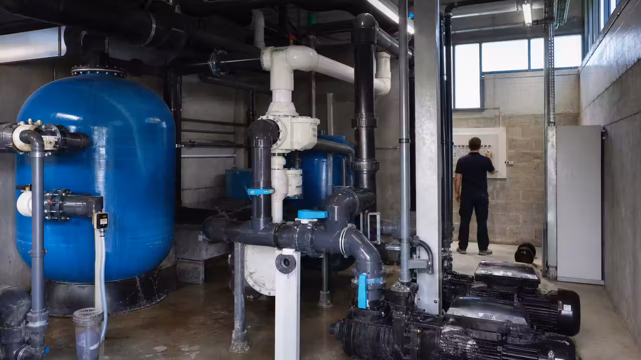 Local technique lumineux d’une piscine municipale avec pompes, filtres, vannes et conduites de traitement d’eau