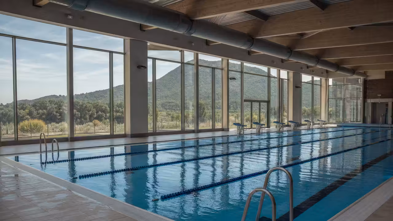 Bassin de piscine publique lumineux avec lignes d’eau et vestiaires visibles à l’arrière-plan