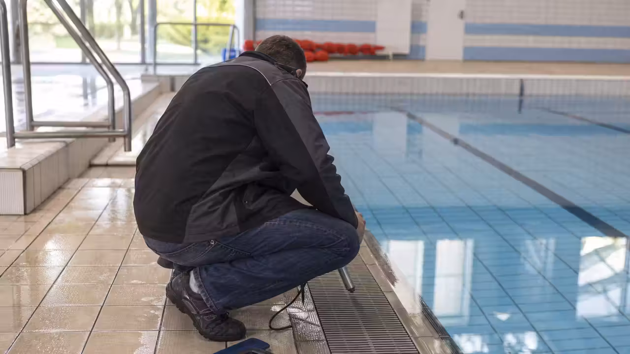 Technicien contrôlant le niveau d’eau et les équipements d’un bassin municipal en cours de maintenance