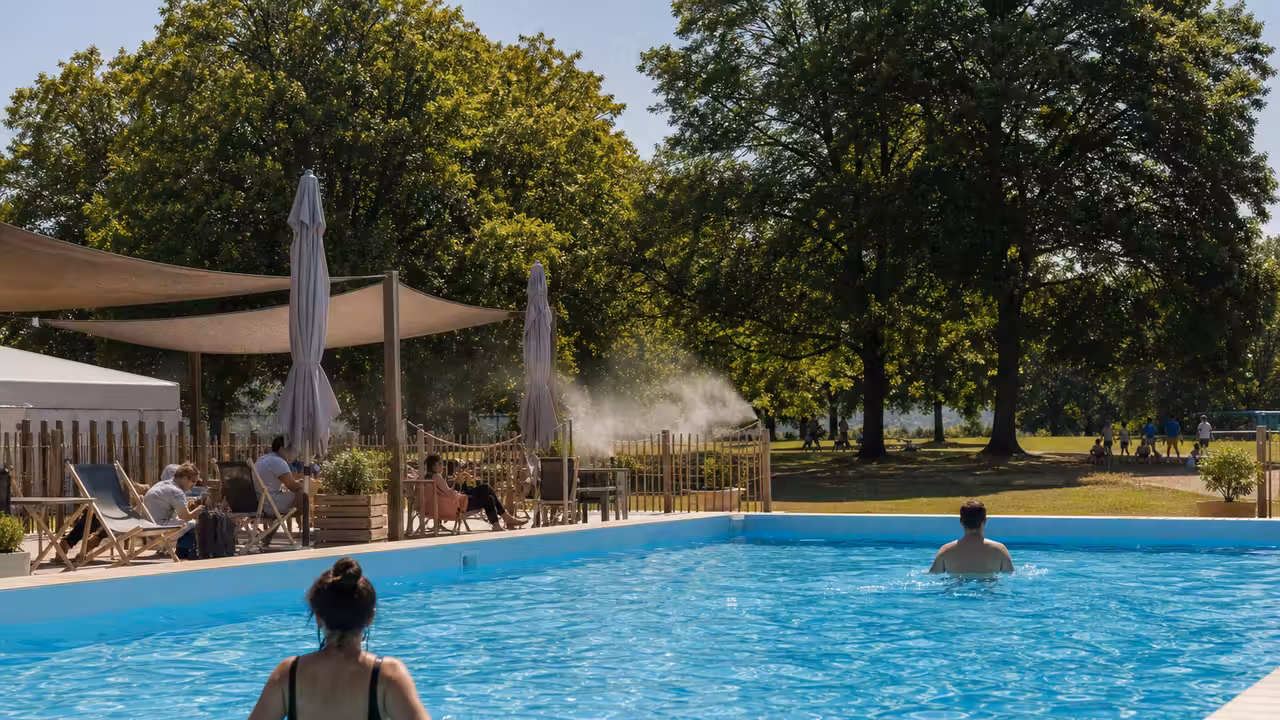 Bassin temporaire en plein air dans un parc urbain, avec transats, brumisation et végétation estivale