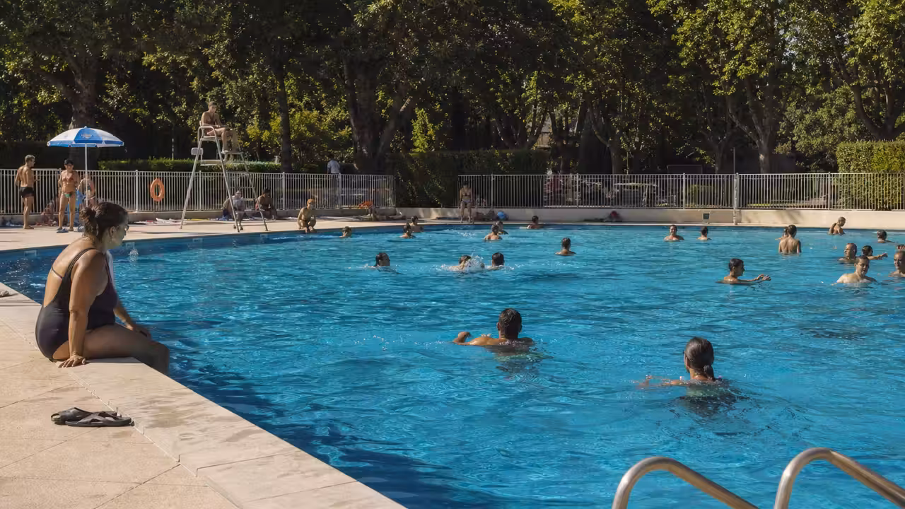 Bassin extérieur d’une piscine municipale animé par des nageurs et des familles durant une journée d’été