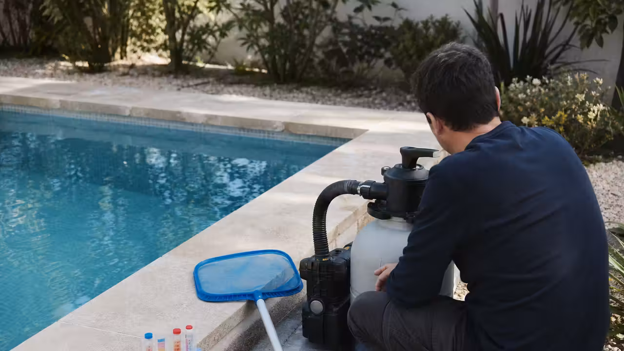 Propriétaire contrôlant la filtration et la qualité de l'eau d'une piscine au début du printemps