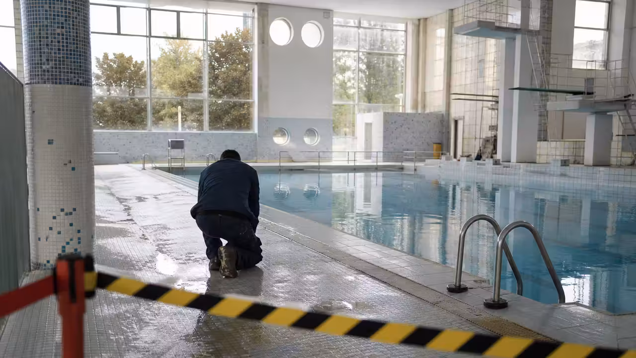 Couloir désert d’une piscine municipale, plages carrelées humides et panneaux de fermeture en arrière-plan