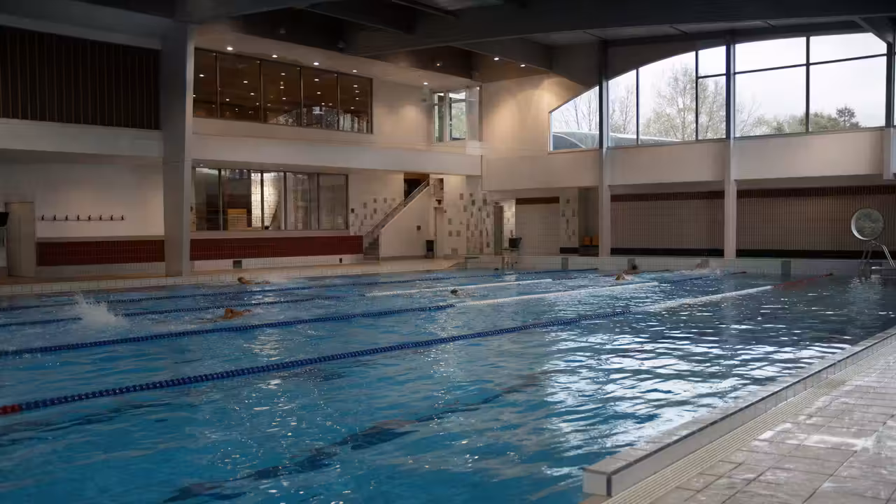 Bassins couverts et lignes d’eau d’une piscine municipale, vus depuis la plage avant l’ouverture