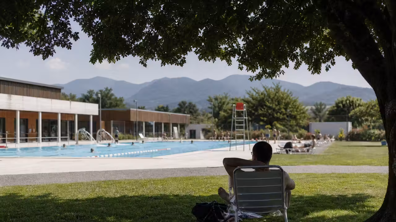 Bassin extérieur d’une piscine publique avec baigneurs et espaces verts en été à Saint-Gaudens
