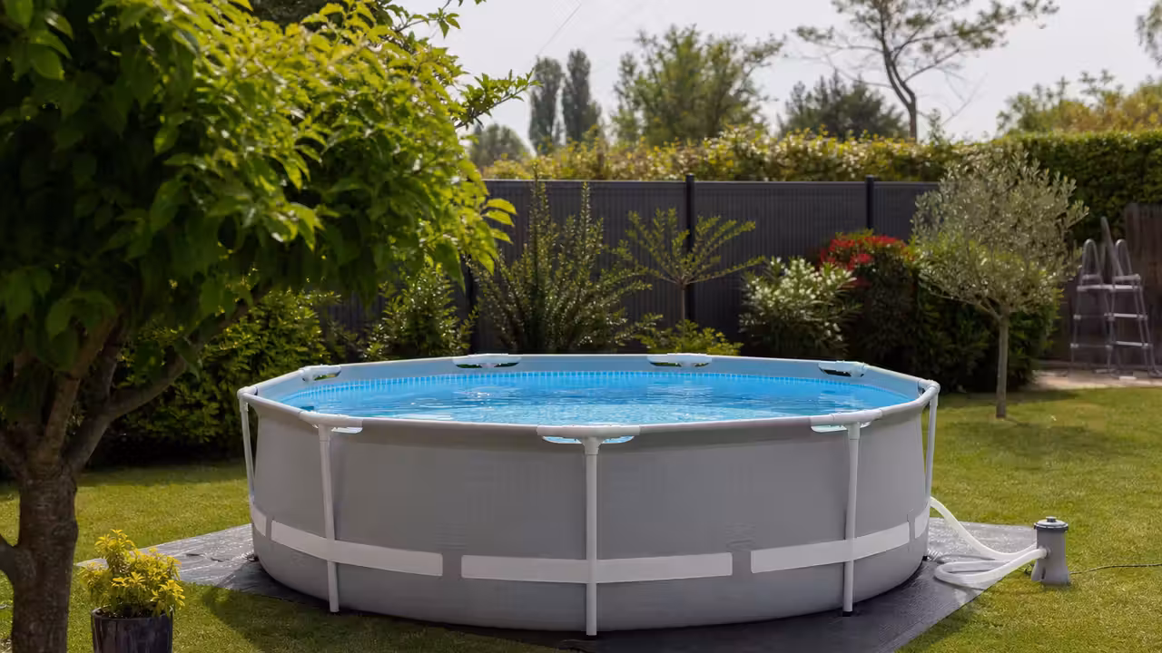 Piscine hors sol tubulaire ronde sur un jardin plat, avec tapis de sol et filtration à proximité