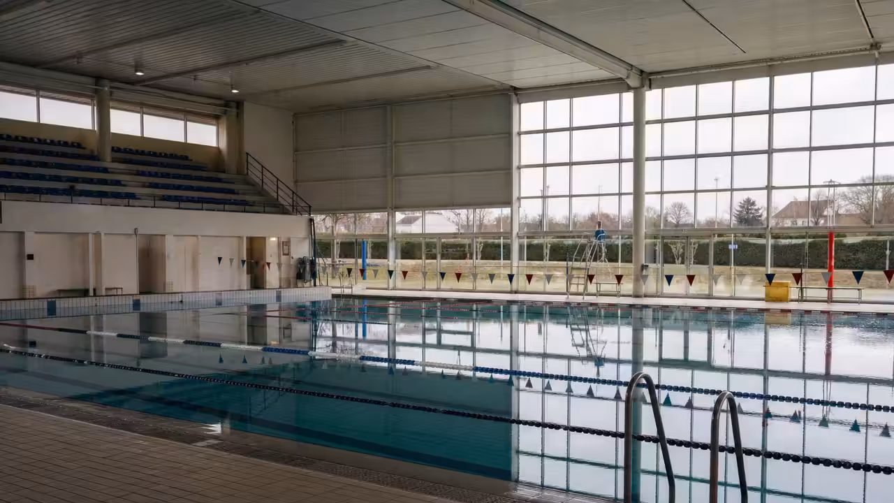 Bassin sportif couvert fréquenté par des nageurs dans un centre aquatique municipal lumineux