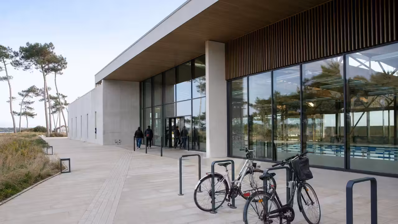 Vue extérieure d’un centre aquatique public contemporain avec bassin et aménagements paysagers