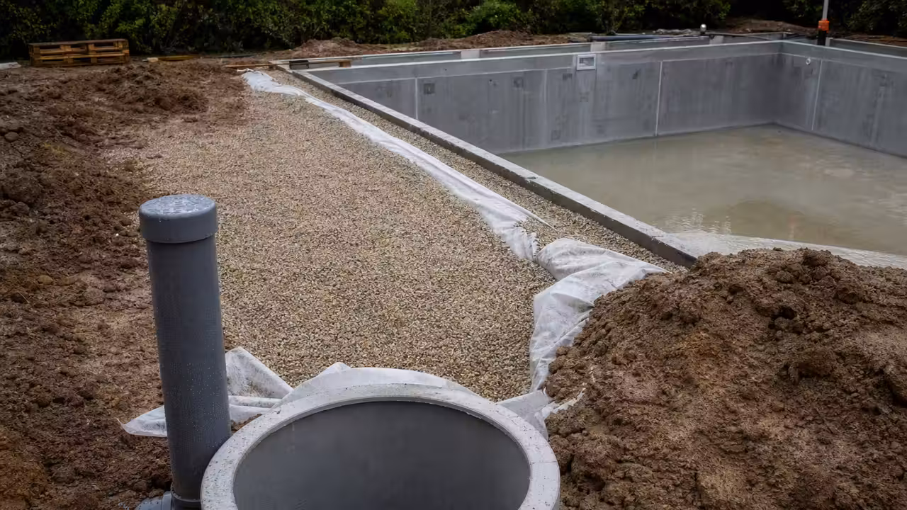 Regard de décompression ouvert près d’une piscine en construction sur un terrain humide et drainé