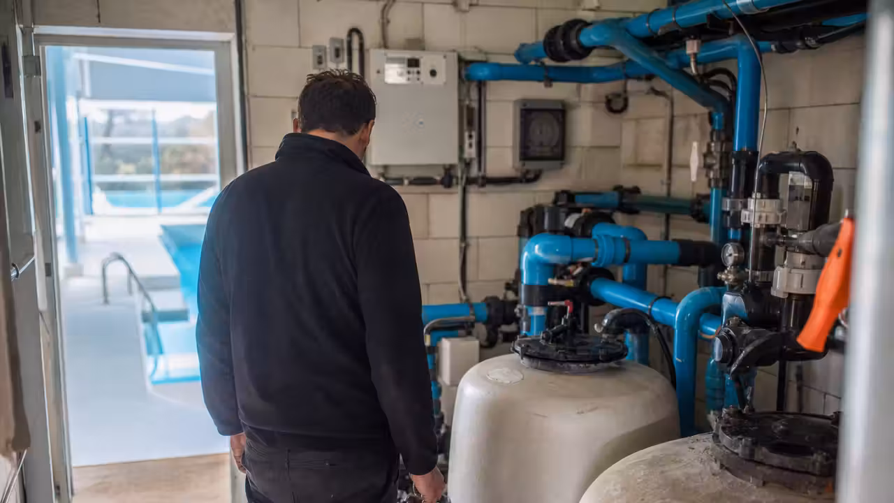 Technicien contrôlant les équipements de filtration d’une piscine municipale dans un local technique entretenu