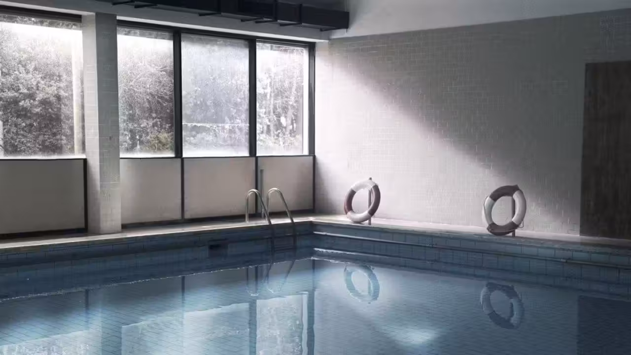 Barrière transparente verrouillée autour d’une piscine familiale enterrée sur une terrasse en bois