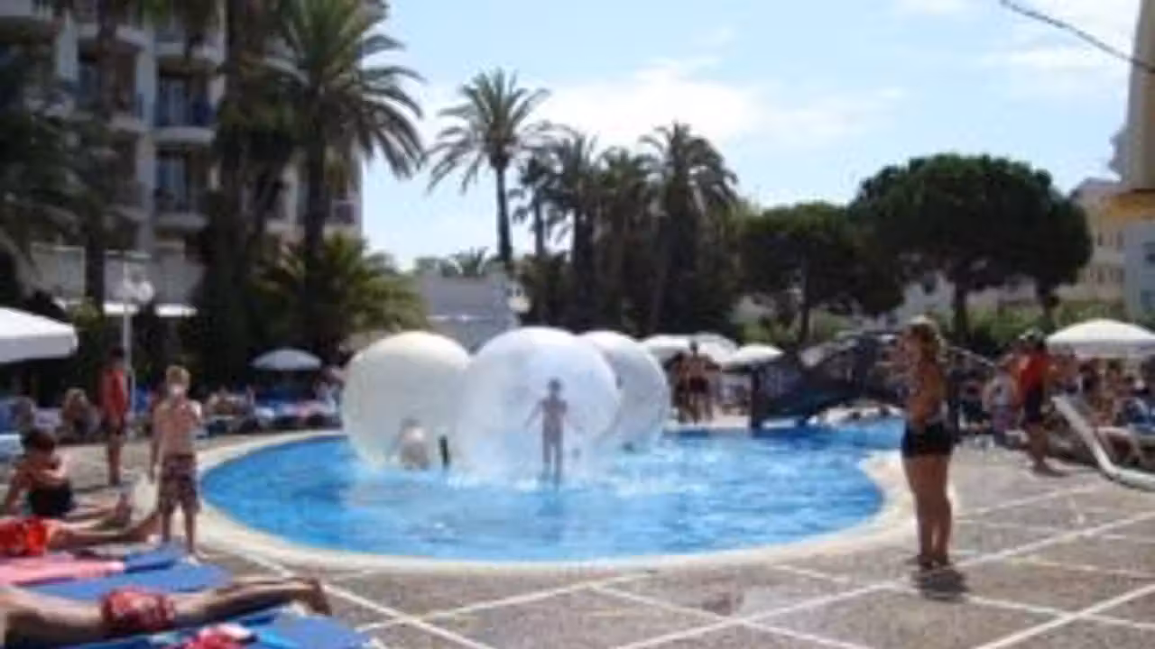 Ballons, panier flottant et frites rangés au bord d’une piscine familiale sous surveillance